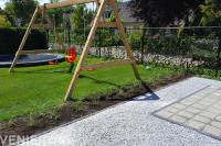 Gazon met trampoline en schommel