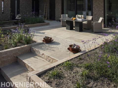 Terras van lichte keramische tegels met tuinmeubilair
