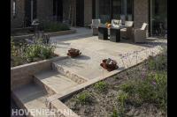 Terras van lichte keramische tegels met tuinmeubilair