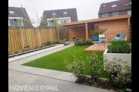 Moderne achtertuin met bestrating, kunstgras, overkapping en vlonder