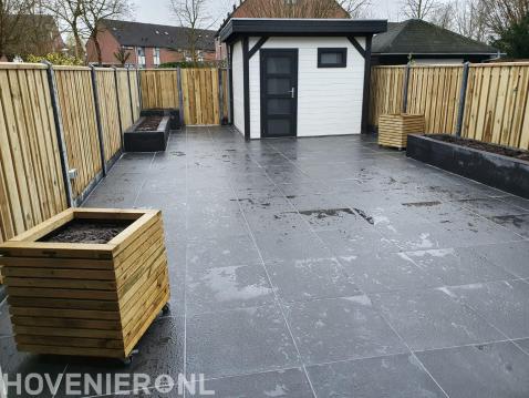 Tuinaanleg met bestrating, plantenbakken, tuinhuis en schutting