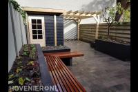 Achtertuin met houten schuurtje met pergola en maatwerk houten bankje