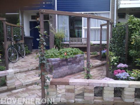 Voortuin met bestrating van oude stenen en houten pergola