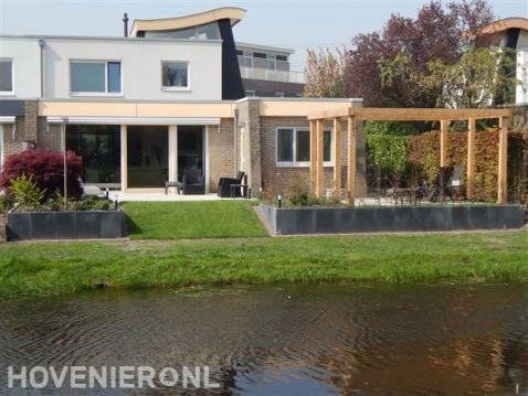 Tuin aan het water met pergola, terras en keerwand