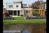 Tuin aan het water met pergola, terras en keerwand