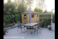 Achtertuin met betontegels in wildverband en houten tuinhuis