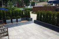 Strakke voortuin met sierbestrating en haagplanten
