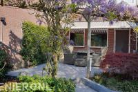 Achtertuin met keramische tegels en pergola