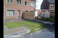 Tuin met verhoogde borders en gazon van graszoden met stapstenen