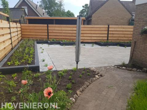 Tuinaanleg met verhoogde borders, bestrating en houten schutting