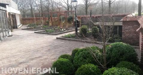 Tuin met houten pergola's en bestrating van waaltjes