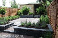 Achtertuin met hoogteverschillen en plantenbakken van stapelblokken
