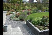 Tuin met gazon, plantenbak van stapelblokken en kleurrijke planten