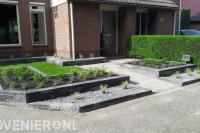 Voortuin met grasveld en verhoogde plantenbakken van stapelblokken