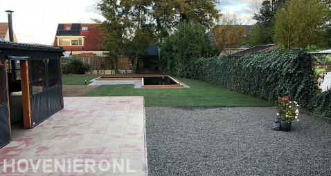 Tuin met overkapping bij terras, gazon en vijver