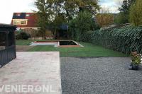 Tuin met overkapping bij terras, gazon en vijver