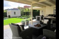 Terrasoverkapping met bestrating van grote tegels en tuinmeubels