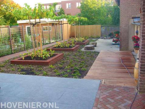 Achtertuin met terras, houten vlonder en hedera schutting