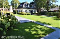 Tuin met groot gazon, terras en vijver