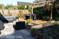 Achtertuin met bestrating van klinkers en houten vlonder met pergola