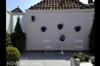 Kleine achtertuin met bestrating van lichte tegels en bloempotten 2