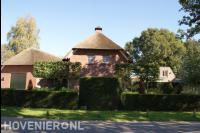 Voortuin met leibomen en strak gesnoeide haag