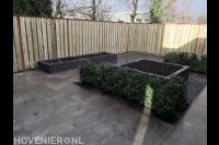 Tuinaanleg met siertegels, plantenbakken en houten schutting