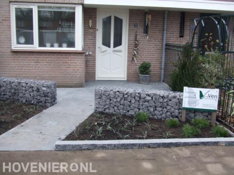 Onderhoudsarme voortuin met grote tegels en schanskorven 1