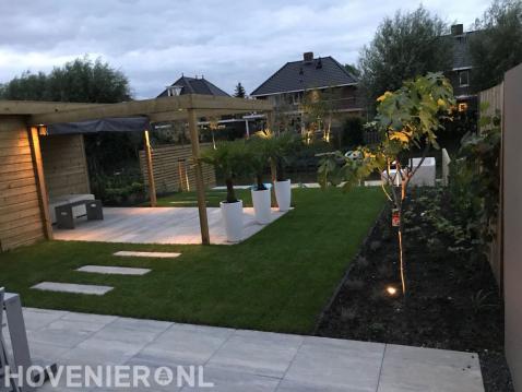 Moderne tuin met sierbestrating, gazon en houten pergola