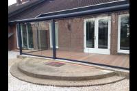 Terrasoverkapping met glazen wanden en houten vlonder