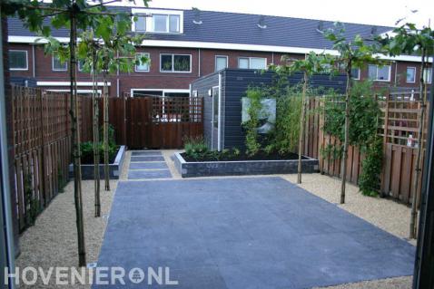 Achtertuin met bestrating, grind, bloembakken en dakplatanen