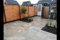 Tuinaanleg met sierbestrating, hout beton schutting en hedera schuttin
