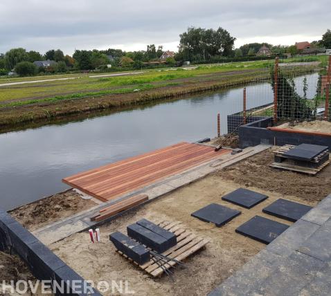 Tuinaanleg met bestrating en houten vlonder aan het water