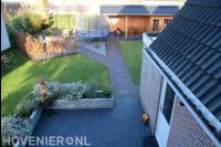 Tuin met terras, gazon en houten kapschuur met berging
