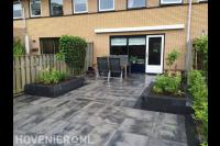 Achtertuin met natuursteen tegels en bloembakken van stapelblokken