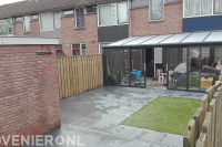 Achtertuin met terrasoverkapping, bestrating en kunstgras