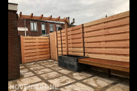 Tuinaanleg met bestrating, pergola en houten schutting met poort
