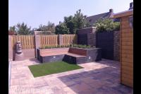 Relaxtuin met zitbank, kunstgras, schuurtje en steenschuttingen 2