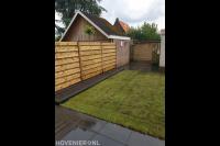 Achtertuin met bestrating, gazon van graszoden en houten schutting