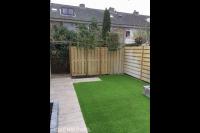 Tuinaanleg met kunstgras, bestrating, leibomen en schutting