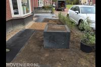 Tuinaanleg met grind, grote siertegels, plantenbak en haag
