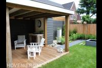 Houten overkapping met vlonder en witte tuinmeubels