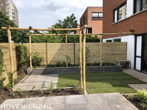 Achtertuin met bestrating, gazon en grote pergola van kastanjehout