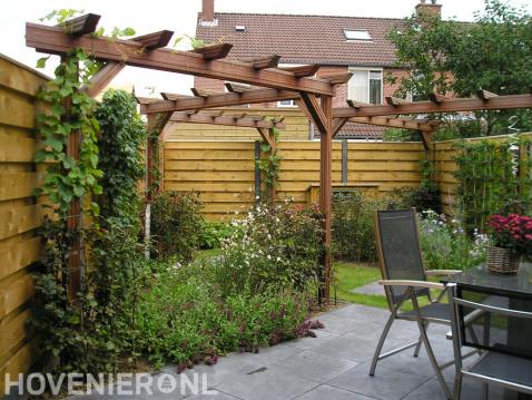 Tuin met schutting, houten pergola's en terras