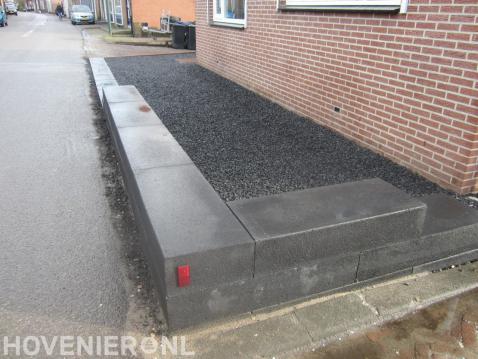 Tuin aan zijkant woning met split en randen van stapelblokken