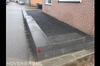 Tuin aan zijkant woning met split en randen van stapelblokken