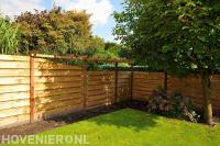 Achtertuin met gazon, houten schutting en pergola
