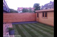 Tuinaanleg met graszoden en houten vlonder, schutting en tuinhuis