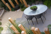 Kleine achtertuin met grind, betontegels en decoratie van houten palen