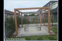 Graszoden, schutting van betongaas en zithoek met houten pergola